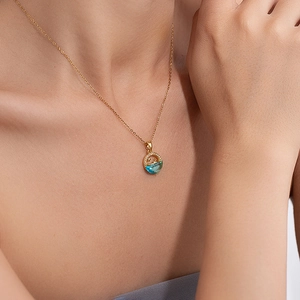 Close-up of gold star and moon necklace with a semi-circular blue gemstone and zircon detail