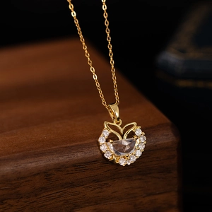 Gold fishtail necklace with moon-shaped zircon pendant on luxury walnut jewelry display