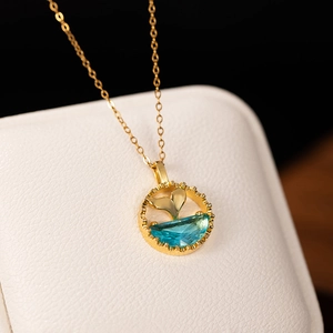 Exquisite gold fishtail necklace with blue zircon pendant on a textured jewelry box