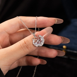 Sparkling silver mermaid tail necklace with zircons held in hand against navy box