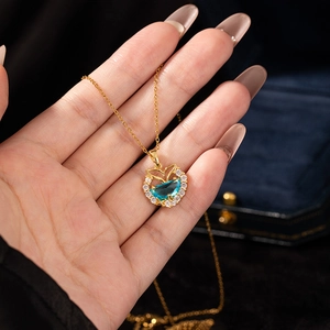 Detail of mermaid tail necklace with blue gemstone and zircons held on hand
