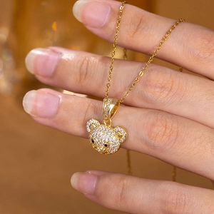 Detailed close-up of a golden teddy bear pendant encrusted with sparkling cubic zirconia
