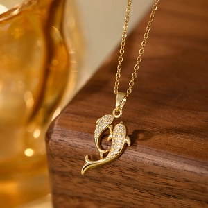 Gros plan du collier pendentif double dauphin doré serti de zircons et chaîne fine