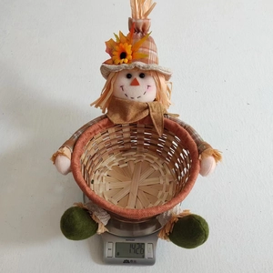 Close-up of scarecrow autumn harvest basket weighing 142.6g on a scale for home decor