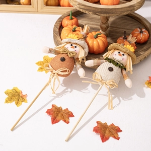 Dettaglio di spaventapasseri decorativi con zucche autunnali e foglie d'acero sullo sfondo
