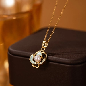 Makroaufnahme von Goldlotus-Anhänger mit blauen Emaille-Blüten und weißer Perle