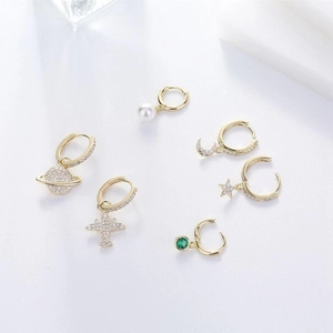 Close-up of gold hoop earrings set featuring star, moon, plane, and pearl charms