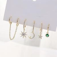 Detail of six-piece gold star and moon earring set featuring green gemstone and chains
