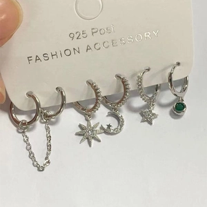Detail view of 925 silver stud earring set featuring stars, moon and green gemstone charms