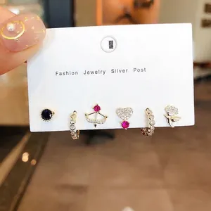 Detail of a six-piece gold-toned earring set featuring stars and birds on a display card
