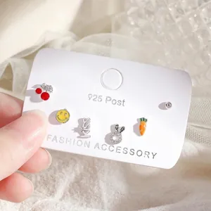 Close-up of 925 silver stud earrings set featuring cherry, smiley face, and rabbit charms