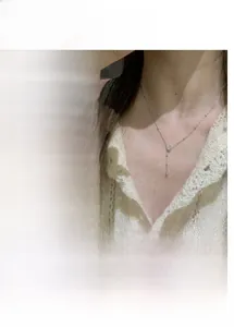 Detailed view of gold Y-shaped necklace with round beads and pear-shaped clear pendant
