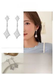 Macro detail of silver brushed rhombus earrings featuring intricate starburst engraving
