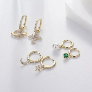 Detailed close-up of six-piece asymmetric gold earring set with celestial zircon charms