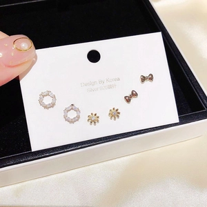 Detail of 6-piece gold earring set with zircon butterfly and flower on a display card