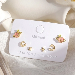 Detailed view of hollow star and moon earrings with pink enamel peach planet on card
