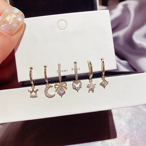 Detail of six-piece gold earring set with zircon moon and star motifs on silver posts