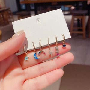 Detail of 6-piece gold earrings set with star, moon, and zircon charms on display card