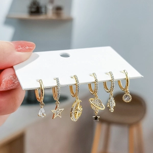 Close-up of gold hoop earrings set with hollow star, moon, and zircon-studded astronaut charms