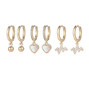 Detailed view of three pairs of gold-plated earrings with heart and lightning bolt charms