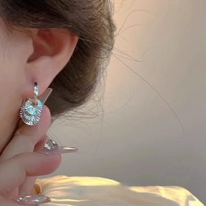 Silver textured fan-shaped hoop earrings for women shown worn in warm natural sunlight