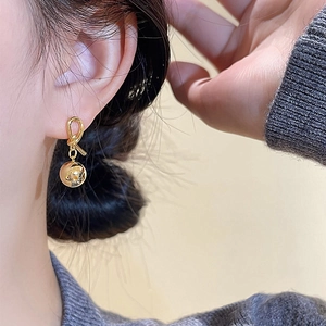 Close-up of a model wearing French vintage gold rope knot ball earrings with high luster