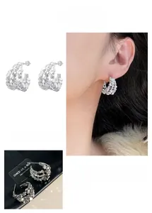 Detailed close-up of layered irregular silver stud earrings with light-reflecting surfaces