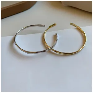 Detail of irregular textured open bangles in gold and silver finish with hammer pattern