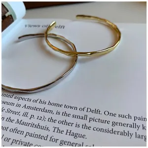 Minimalist silver and gold hammered textured open bangles displayed on a vintage book