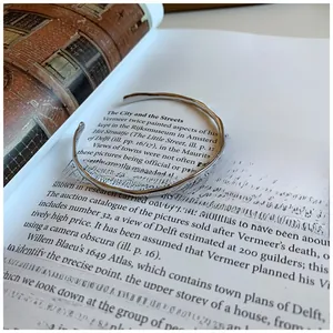 Detail of 925 silver irregular hammered texture open bangle on an aesthetic book background