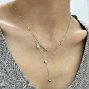 Collier double couche français avec pendentif croix et perle sur un modèle élégant