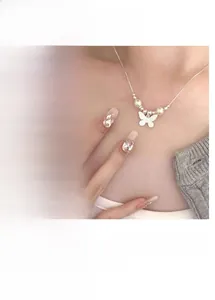 Dettaglio del ciondolo a farfalla d'argento con perle bianche e catena fine della collana