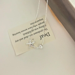Close-up of silver starfish pendant with small pearl on a delicate snake chain necklace