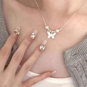 Elegante collana con ciondolo a farfalla in argento e perle bianche indossata da modella