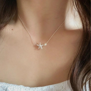 Elegant starfish and pearl necklace on model collarbone, minimalist silver design for women
