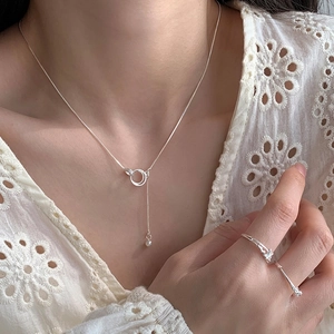 Silver lariat necklace with interlocking rings and bead pendant worn by a model