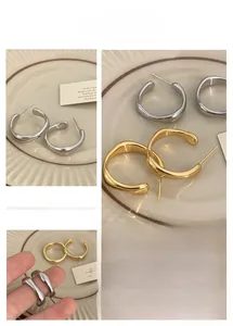 Détail de boucles d'oreilles minimalistes en U dorées et argentées sur plat céramique