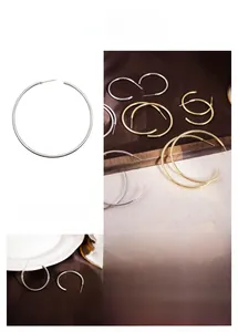 Detailed view of C-shaped metal hoop earrings in polished gold and silver finishes