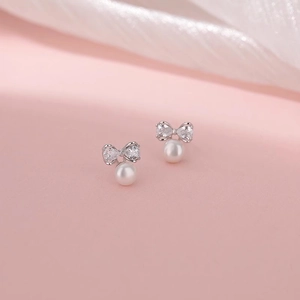 Détail de boucles d'oreilles nœud en argent avec zircons brillants et perles blanches