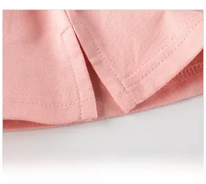 Detail of pink knit shirt hem featuring precise double-stitch sewing and side slit design