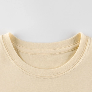 T-shirt beige pour enfants à col rond montrant les détails de couture et la maille fine