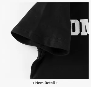 Detail of double-stitched hem and white DN logo print on a black cotton kids T-shirt