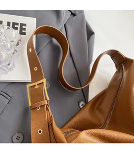 Detail of brown litchi pattern leather hobo bag with adjustable strap and gold buckle
