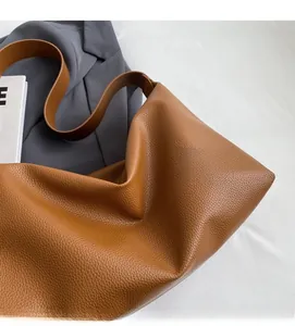 Close-up of brown litchi pattern leather tote bag with soft texture and wide shoulder strap