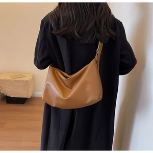 Close-up of vintage brown leather hobo bag with gold buckle on adjustable strap