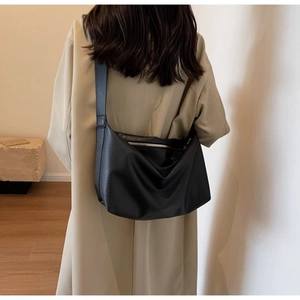 Detail of black pebbled leather tote bag with wide strap and silver metal zipper
