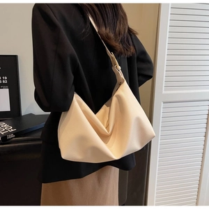Detail of creamy white faux leather hobo bag with litchi texture and golden buckle strap