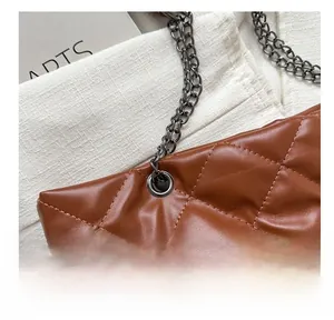 Detalle del bolso tote marrón acolchado con cadena de metal oscuro y ojales