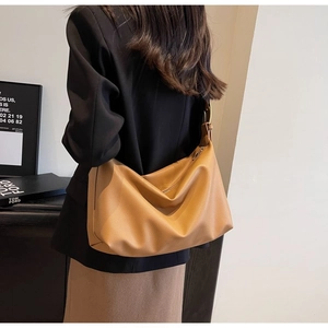 Detail of a brown lychee-grain leather hobo bag with gold hardware buckle and soft folds