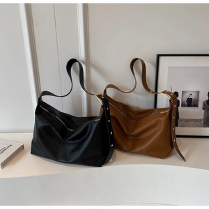 Detail of classic black and brown leather hobo bags with textured finish and metal eyelets